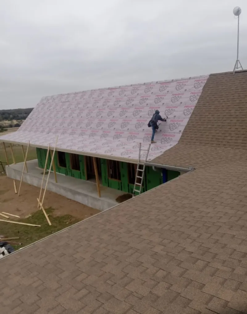 Worker preparing underlayment for a metal roof installation in Port Sheldon